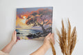 A vibrant sunset painting with an orange and red leafy tree overlooking a coastal seascape with gentle waves and cliffs.