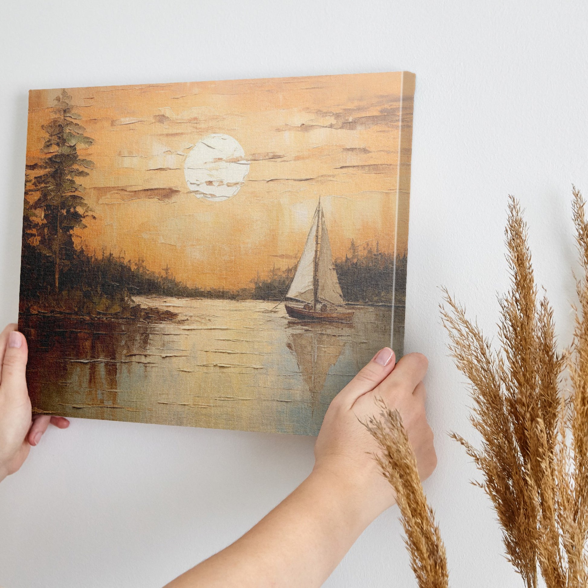 Canvas print of a sunset with orange skies, sailboat on calm lake, and tree silhouettes