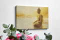 Framed canvas print of a Golden Buddha statue sitting in meditation by the water