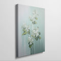 Framed canvas print of white blossoms with green leaves on a soft blue background