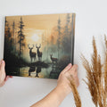 Framed canvas print of deer silhouetted against a forest sunset with reflections on water