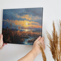 Framed canvas print of an impressionistic sunset over a coastal landscape with vibrant warm hues