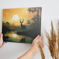 Framed canvas print of a majestic stag against a forest lake at sunrise with orange skies