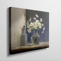 Framed canvas print of white flowers in glass vase with vintage bottle on a neutral background