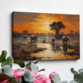 Framed canvas print of African elephants walking beside water during a vibrant sunset