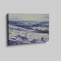 Framed canvas print of a snowy countryside landscape with rolling hills in cool blue tones