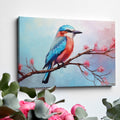 Framed canvas print of a colourful Kingfisher bird on a branch with pink cherry blossoms against a soft blue sky