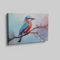 Framed canvas print of a colourful Kingfisher bird on a branch with pink cherry blossoms against a soft blue sky