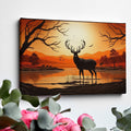 Printed canvas art of a black deer silhouette against an orange sunset with trees and mountains