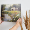 Framed canvas print of a rustic cottage by a peaceful lake with wildflowers in the foreground