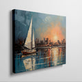 Framed canvas print of an impressionist painting with a sailboat against a sunset cityscape reflecting on the water