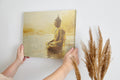 Framed canvas print of a Golden Buddha statue sitting in meditation by the water