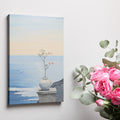 Canvas print of a tranquil ocean view with a blossoming plant in a vase on a ledge