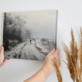 Framed canvas print of a winter landscape with a snowy path and figures walking, in a monochrome colour scheme