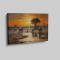 Framed canvas print of African elephants walking beside water during a vibrant sunset