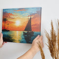 Framed canvas print of a tropical sunset with a sailboat and palm trees