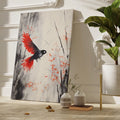 Framed canvas print of a stylised bird with vibrant red wings against a monochrome watercolor background