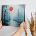 Framed canvas print of a mysterious blue forest with a vibrant red moon and a lone silhouette reflected on the water