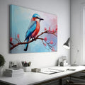 Framed canvas print of a colourful Kingfisher bird on a branch with pink cherry blossoms against a soft blue sky