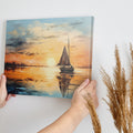 Framed canvas print of sailboat against golden sunset with peaceful ocean reflection