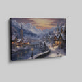 Framed canvas print of a snowy Alpine village at twilight with warm glowing cottages and snow-capped mountains