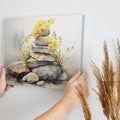 Framed canvas print of watercolour stones stacked with yellow flowers