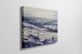 Framed canvas print of a snowy countryside landscape with rolling hills in cool blue tones