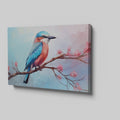 Framed canvas print of a colourful Kingfisher bird on a branch with pink cherry blossoms against a soft blue sky