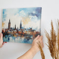 Framed canvas print of abstract watercolour cityscape with vibrant blue, orange and black tones