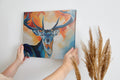 Framed canvas print of a stylized stag with abstract blue and orange background