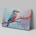 Framed canvas print of a colourful Kingfisher bird on a branch with pink cherry blossoms against a soft blue sky