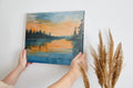 Framed canvas print of a watercolor sunset landscape with reflections over a calm lake