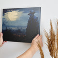 Framed canvas print of a mysterious figure under a moonlit, bird-strewn sky within a dramatic landscape