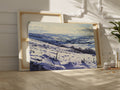 Framed canvas print of a snowy countryside landscape with rolling hills in cool blue tones