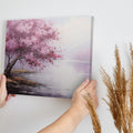 Framed canvas print of an impressionistic cherry blossom tree by a tranquil lake with soft pastel colors