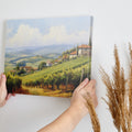 Framed canvas print of a sunny Tuscan landscape with vineyards and rustic houses