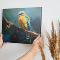 Framed canvas print of a vibrant blue and yellow bird perched on a tree branch with green leaves