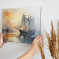 Framed canvas print of an impressionist painting featuring a sailboat against a sunset sea with warm orange and cool blue hues