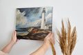 Framed canvas print of a lighthouse by the ocean with dramatic clouds and coastal cliffs