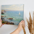 Framed canvas print of an impressionist painting depicting sailing boats on a serene sea beside a coastal cliff