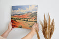 Framed canvas print of impressionistic desert hills with vivid red, earthy beige, and lush green tones