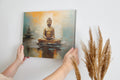 Framed canvas print of a serene Buddha in meditation with warm orange and soft blue abstract background