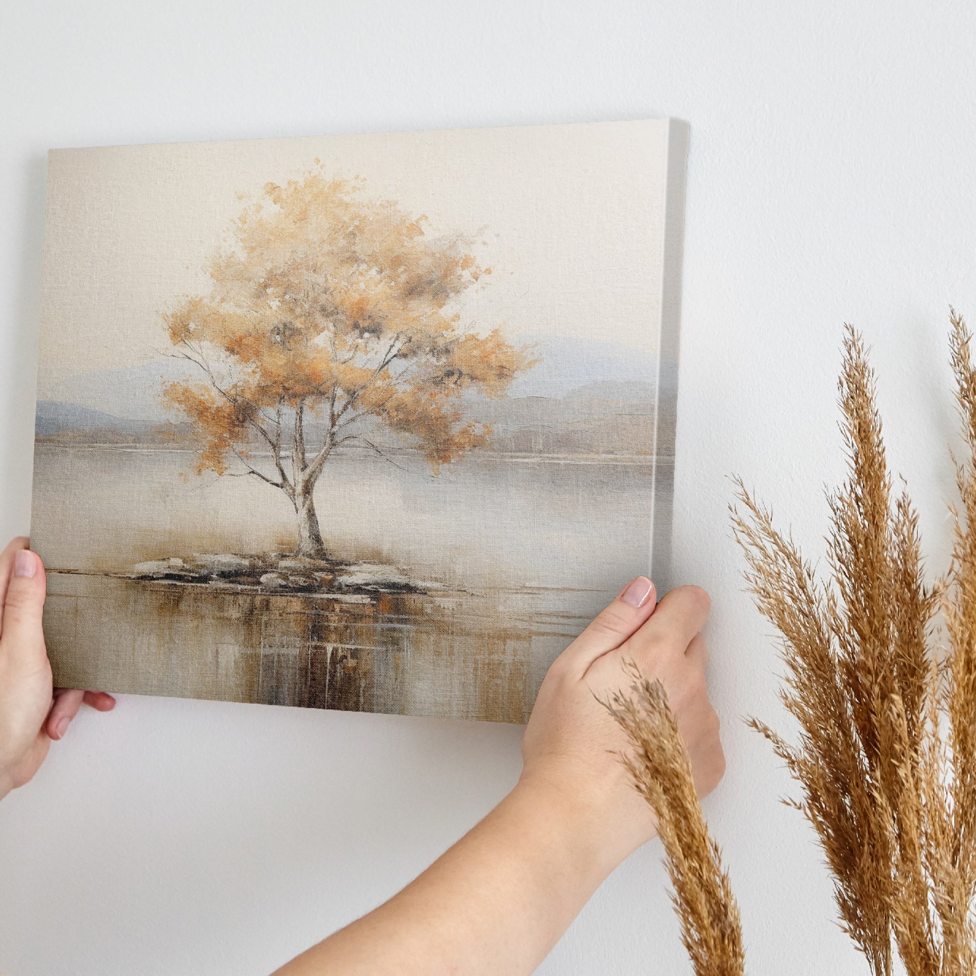 Framed canvas print of a solitary tree with autumn leaves reflected on a calm lake with warm beige, gold, and white tones