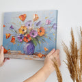 Framed canvas print of textured impasto poppies in a purple vase against a blue background