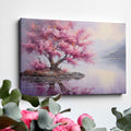 Framed canvas print of a cherry blossom tree by a tranquil lake at dusk with mountains in the background, reflecting soft pink and purple hues