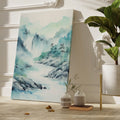 Framed canvas print of a tranquil watercolour painting depicting misty mountains and a serene river landscape in soft blue and green hues.