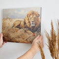 Framed canvas print of a realistic lion lying in the grass of the African savanna, with warm golden tones