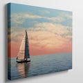 Sailboat on calming ocean waters during a vibrant sunset with orange and pink clouds in the sky.