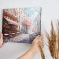 Framed canvas print of a picturesque Parisian alley with cherry blossoms and a street cafe scene in springtime