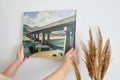 Framed canvas print of a serene countryside bridge over a river with mountain backdrop